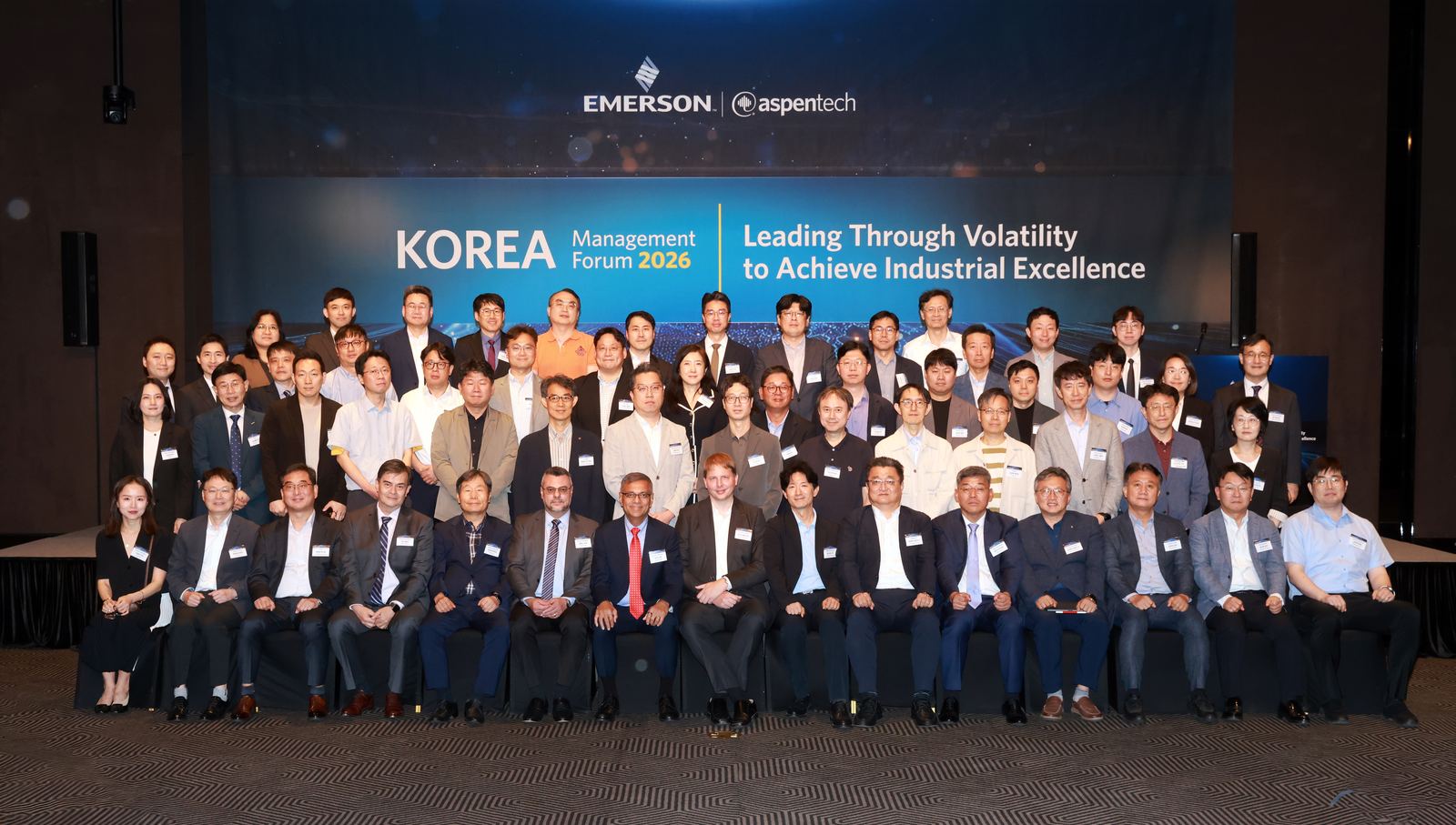 Group photo of forum speakers and attendees in front of the event banner