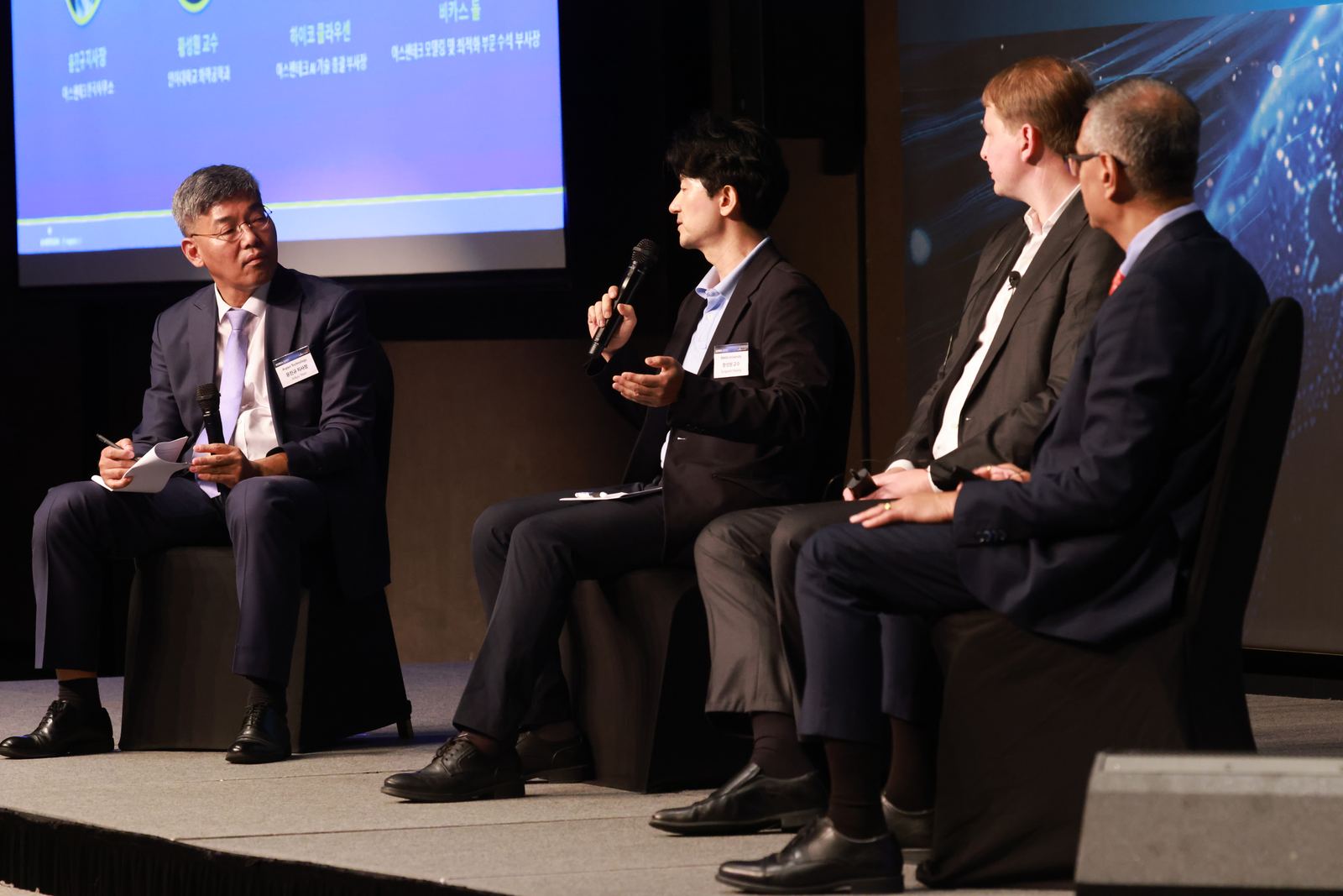 Sean Hwang answering a question with microphone while other panelists listen